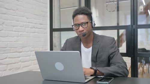 Man Working on Laptop with Headset in Office