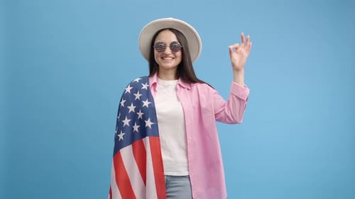 Woman Wearing American Flag Smiling and Gesturing OK