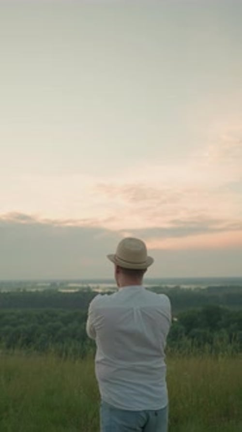 Thoughtful Man Gazing Over a Tranquil Lake at Sunset in a Grassy Field