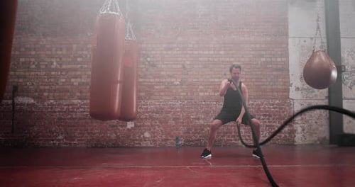 Man Doing Battle Ropes Workout in Gym