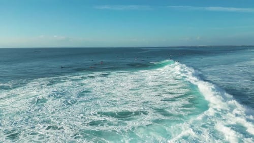 Luftaufnahme der Wellen, die am Balangan Beach Bali gegen die Küste prallen, mit Surfern, die auf den Wellen reiten