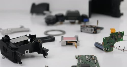 Closeup of disassembled camera spare parts on the desk in workshop. Broken camera for service repair