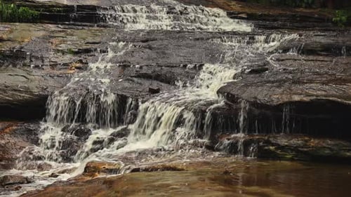 A Stunning Waterfall Cascades Down Mosscovered Rocky Cliffs Surrounded By Lush Green Vegetation The