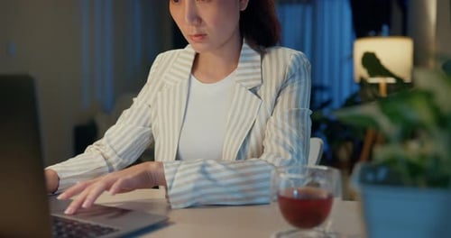 Woman Works on Laptop with Tea at Night