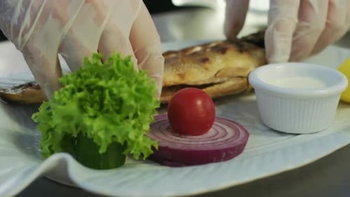Side view close-up of male hands putting fried fish on plate in slow motion. tasty delicious baked