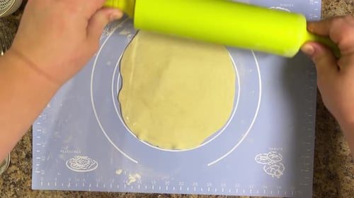 Rolling out round pieces of raw dough with a rolling pin to make patties. Top view.