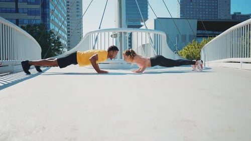 Athletic Couple Doing Pushups Together in City