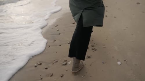 Back View of Happy Woman Running Away on Sandy Sea Beach Girl Wearing in Stylish Green Coat Beige