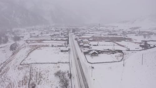 Snowy Mountain Road Crossing Small Village in Winter
