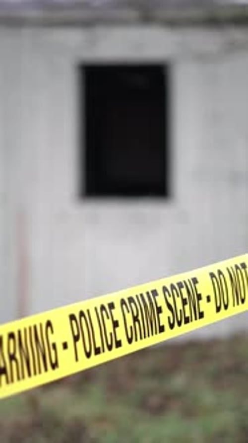 Vertical View of Police Crime Scene Tape in Front of Old WHite Building, Close Up