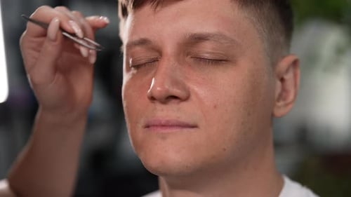 Closeup Face of Handsome Young Man Having Relaxing Eyebrow Shaping Session in Modern Beauty Salon