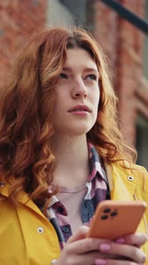 Une jeune femme vêtue d'un imperméable jaune vif appréciant son téléphone dans le paysage urbain