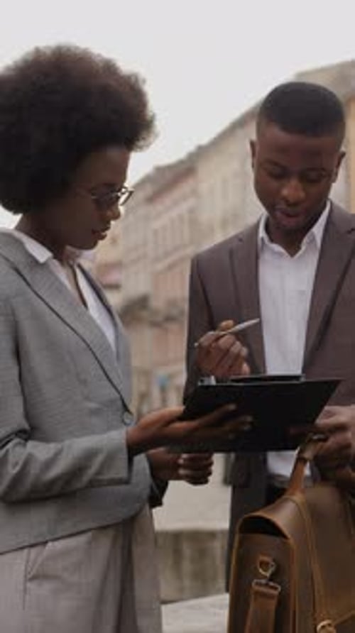 Portrait of Two Busy African People Sign a Contract on Clipboard While Standing on City Street