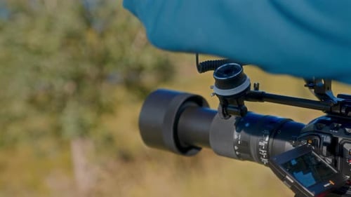 Camera Operator Adjusting Lens Outdoors During Daytime