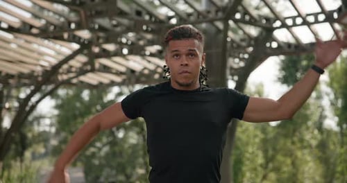 Muscular Man Stretching Arms in Urban Park