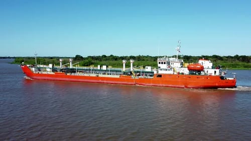 Side Shot Of Huge Long Red Commercial Ship Crossing Narrow Arm Of River, Paraguay