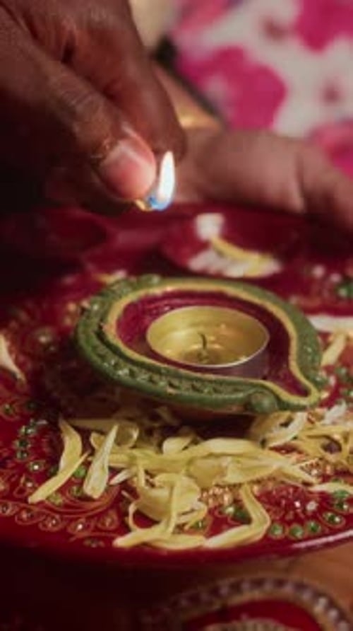 Lighting a Decorative Diya Lamp on a Red Plate