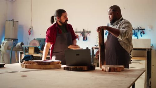 Woodworker Looking Over Blueprints on Laptop Brainstorming with Colleague