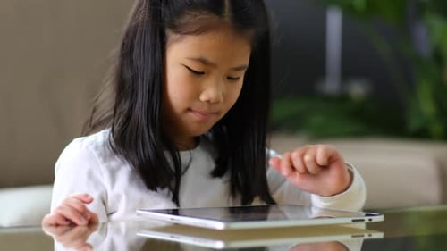 Focused Girl Using Tablet Device at Table