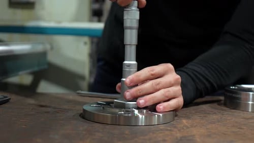 Man Measuring Metal Pieces Using Micrometer at Factory