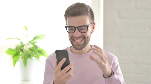 Excited Young Adult Celebrates Success on Smartphone