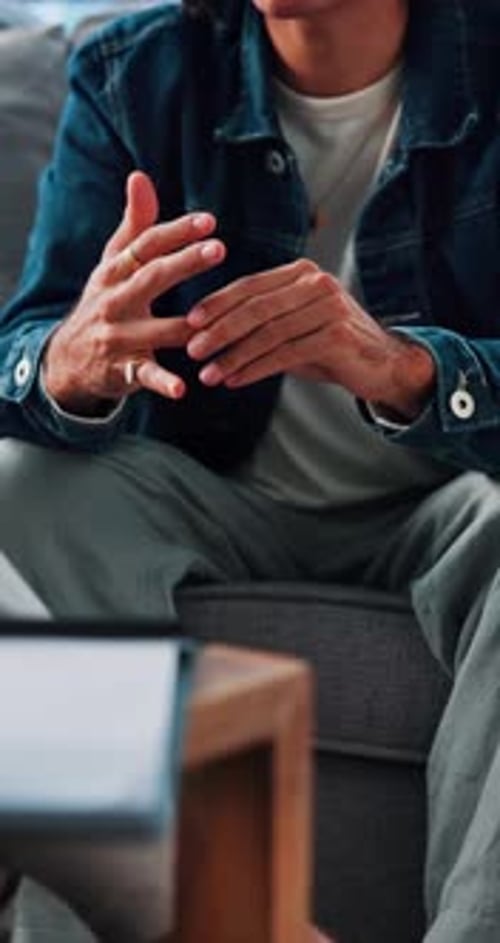 Man Sitting on Couch Gesturing with Hands