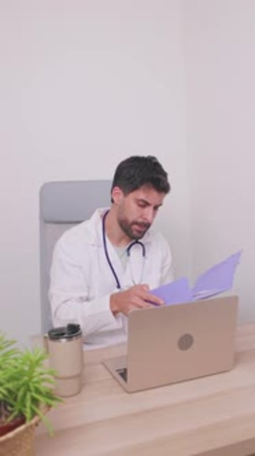 vertical Médecin de sexe masculin télétravaillant à son bureau et examinant les documents du patient
