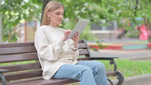 Woman Using Tablet in Park on Bench
