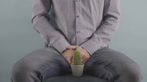 Man Sitting with Cactus Between Legs Close Up