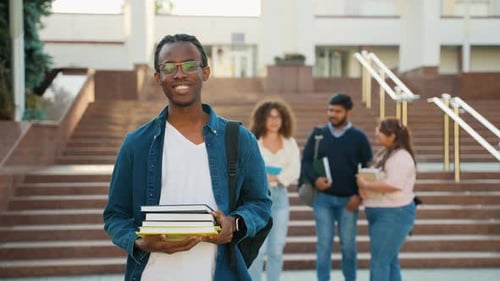 College Student Holds Books in Front of Campus