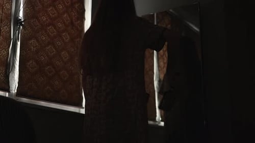 Woman Brushing Hair in Dark Room with Mirror
