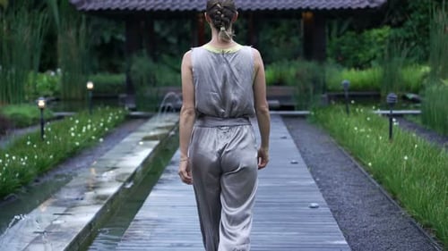 Elegant young woman rambling through a lush green garden on a sunny day