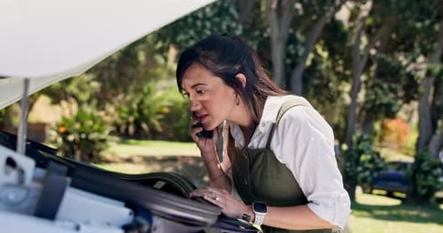 Woman talking on phone at car with open hood