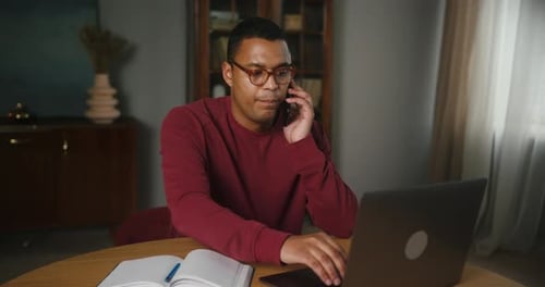 Latin Man Freelancer trabaja en una computadora portátil y llama a su colega