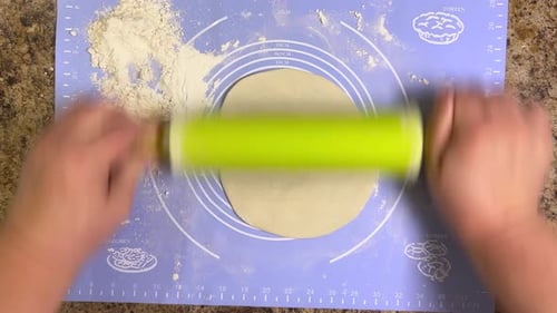 Rolling out round pieces of raw dough with a rolling pin to make patties. Top view.