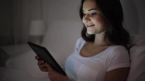 Woman Using Tablet Device in Bed at Night