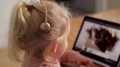 Young Child Watches Tablet with Hearing Aid