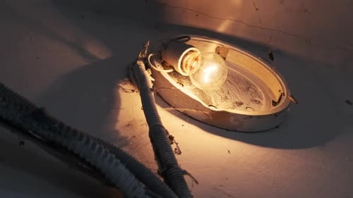Old Incandescent Light Bulb Glows on the Concrete Wall in the Stairwell