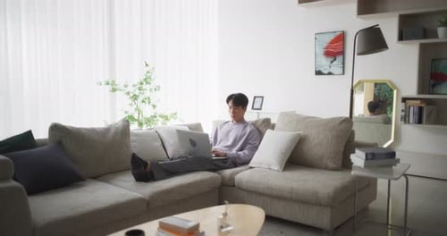 Man Works on Laptop While Sitting on Sofa