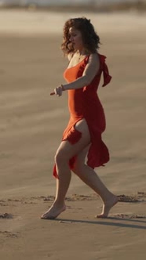 Woman in red dress dancing on the beach