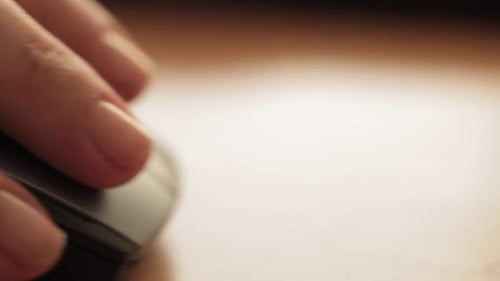 Close-up of a hand gently resting on a computer mouse, focusing on daily technology use