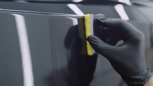 Professional Cleaner in Gloves Close Up Carefully Polishing Smooth Shiny Surface of a Car with