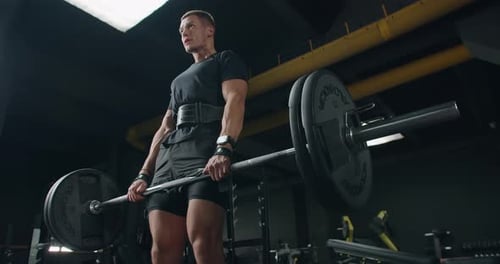 Young athletic man has workout and doing deadlift with barbell in gym