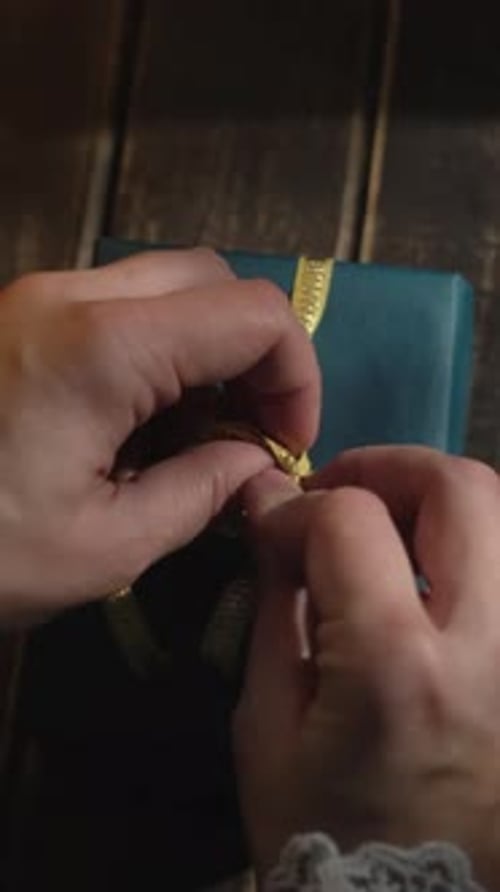 Hands Tie a Gold Ribbon on a Gift