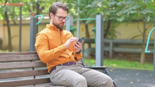 Adult Man Using Smartphone on Park Bench