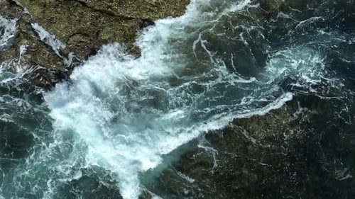 Powerful ocean waves clash against the rocky shore.
