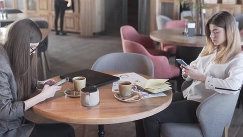 Young Adults Using Smartphones at Cafe Table