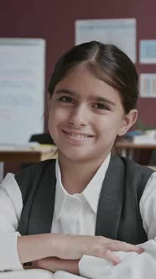 Portrait of Happy Middle Eastern Girl Sitting at Desk in School