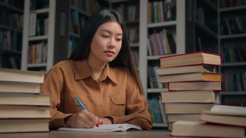 Smart Focused Asian Woman Girl Student Doing Homework at Desk with Books in University Library