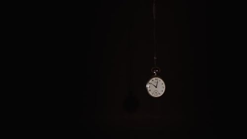 Taschenuhr schwingt auf dunklem Hintergrund